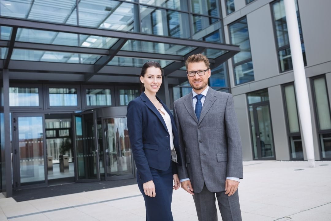 confident-businessman-with-colleague-standing-outside-office-building